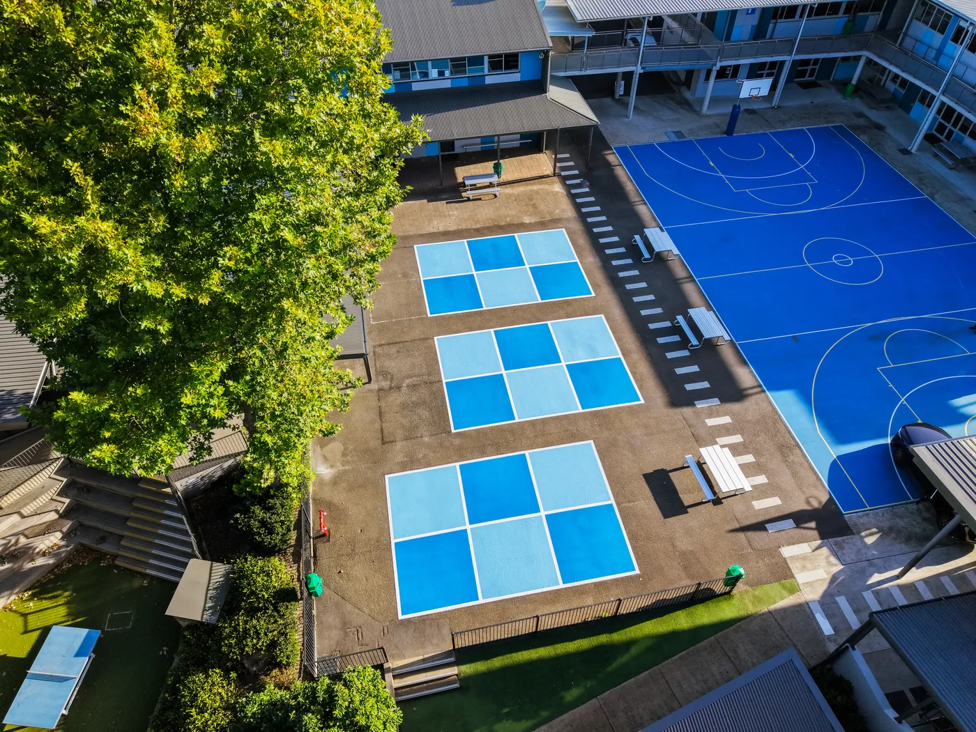 Aerial view of a revived blue school sports court with handball courts