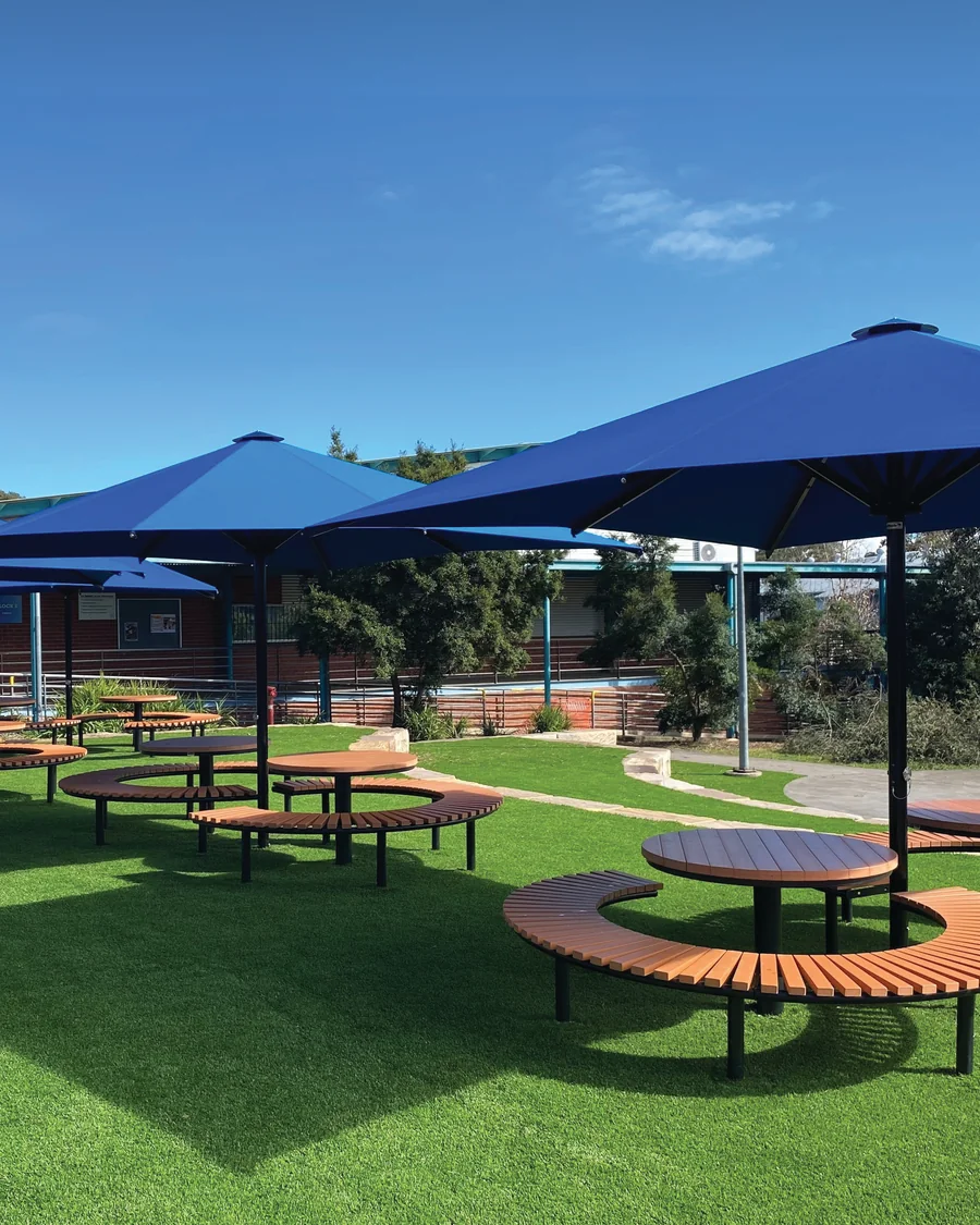 Navy umbrellas over curved outdoor settings on synthetic grass at Quakers Hill High School