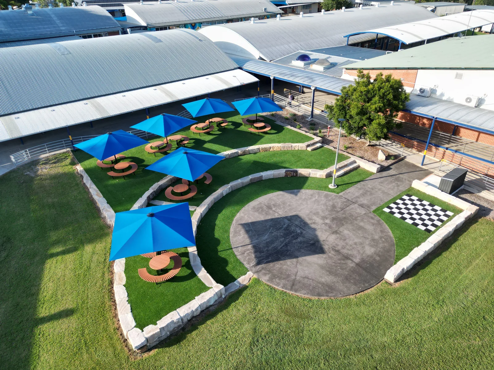 Aerial view of a landscaped school courtyard with synthetic grass and shade umbrellas