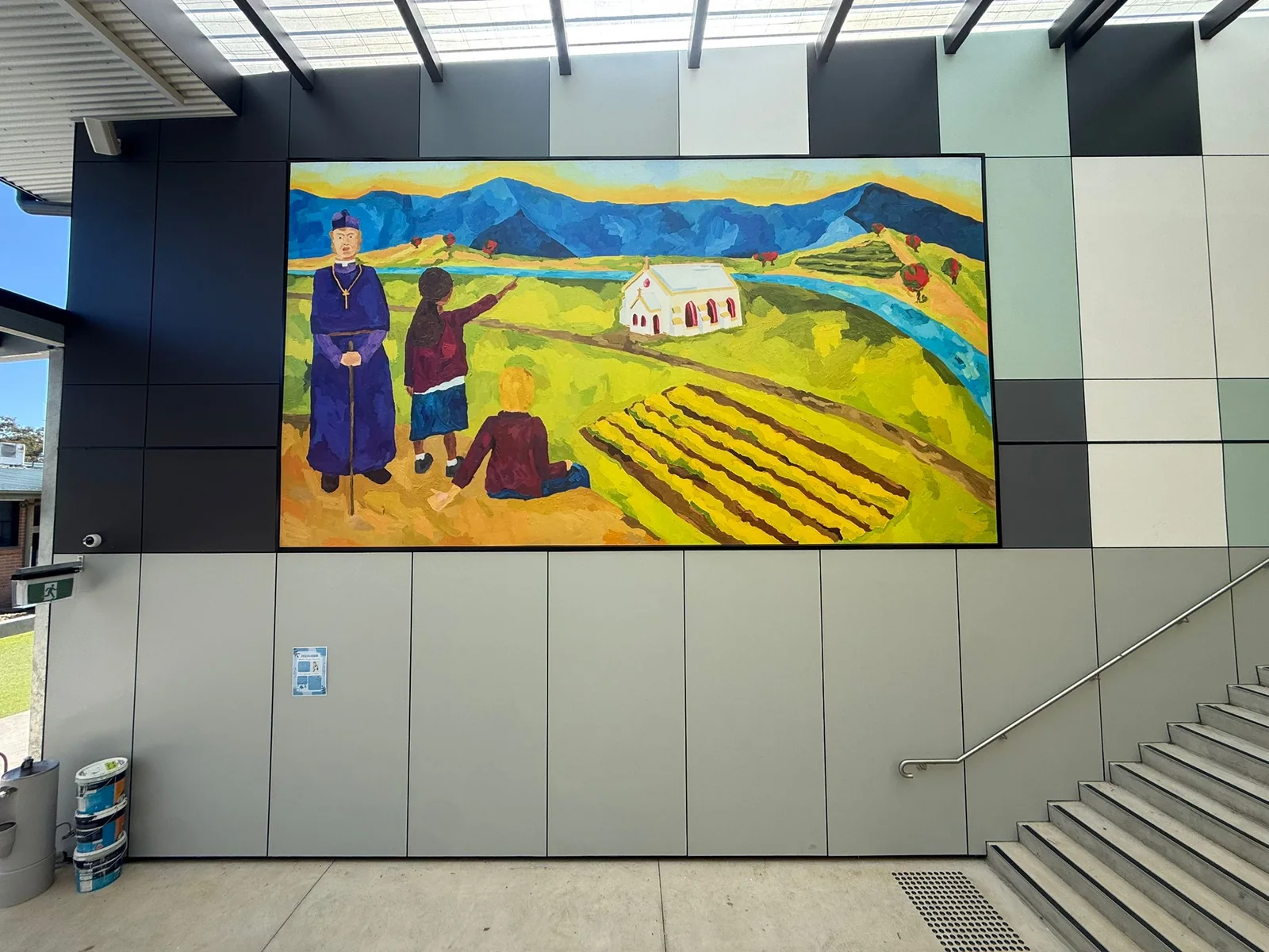 Painted mural of a priest, students, a church and farmland at Bede Polding College
